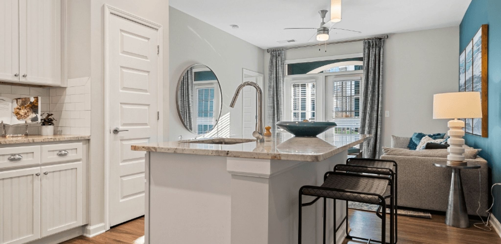 Hawthorne at Westport apartment kitchen with white cabinetry, stainless steel appliances, and kitchen island with 2 chairs